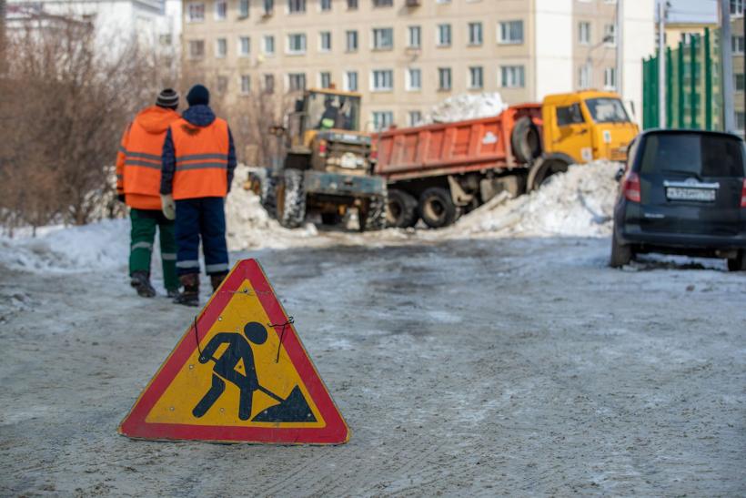 Workers in hi-vis winter gear clearing snow beside a loader