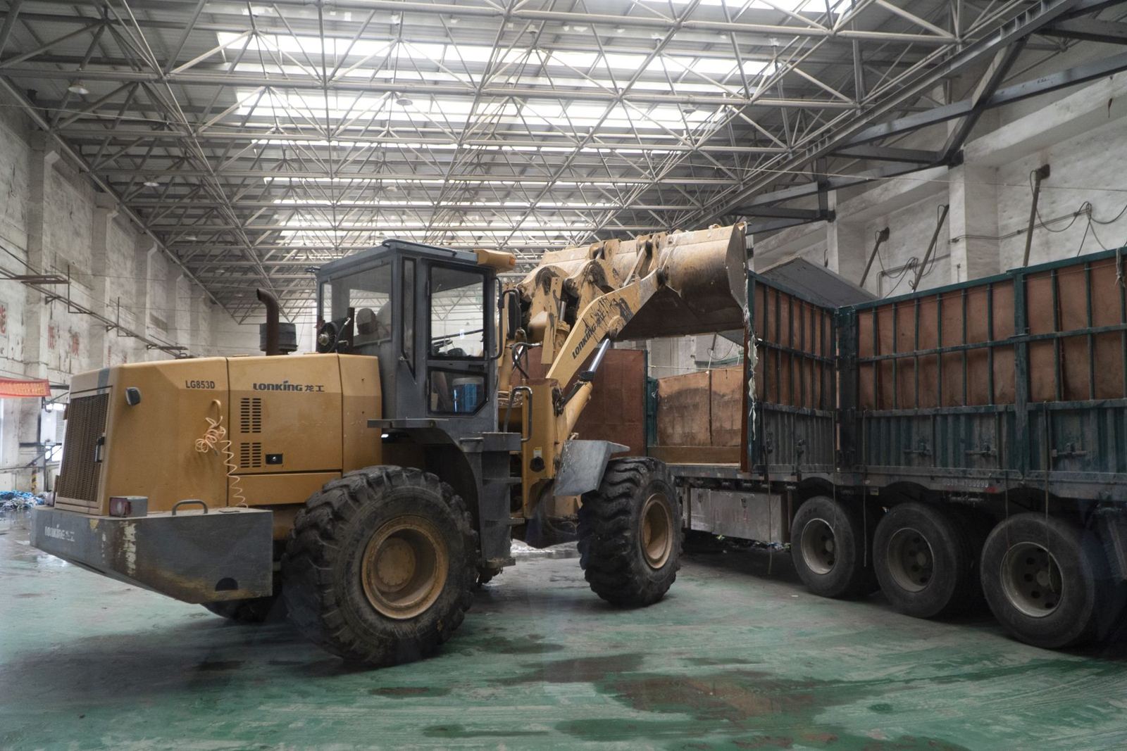 Wheel loader filling a truck with bulk material inside a large covered storage building